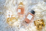 stylish perfume bottles resting on a white fur rug.