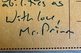 A macro image of a cardboard postcard. Handwritten text reads, “With love, Mr. Primm”.