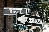 A one-way sign repurposed to say “One day” and pointing left, indicating the road we know we should take but often don’t.