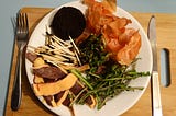 A plate containing what looks like a regular meal but on closer inspection is  a colourful assortment of food scraps, coffee grounds and used matches.