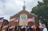 A beautiful church building surrounded by numerous American flags.
