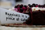 Knife with engravement of “Happiness is a piece of cake” cutting through a cake