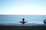 A peaceful woman looking out to the horizon in an infinity pool