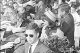 Agent Paul Landis (in sunglassess) monitors the crowd as First Lady Jacqueline Kennedy and President John F Kennedy greet wellwishers in Dallas on November 22, 1963