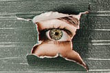Eye peering through ripped paper, focusing on what is in front of them