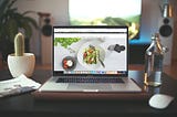 A laptop sits open on a desk. It features a food-related website in progress.