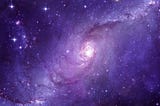 The galaxy swirling colored purple.