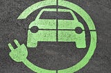 A green electric vehicle charging sign on a parking space