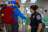 A photograph of a passenger at George Bush Intercontinental Airport in Houston, US, who is scanning their ticket at a biometric station to board a flight