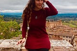 A photo of Yana Kozukhin in a red dress in front of a backdrop of a city.