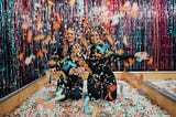 Two girls playing around with confetti.