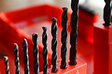 Eight drill bits sitting in a drill bit container