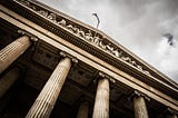 Angled upwards view of front of courthouse with Greek columns and statues