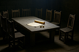 A dimly lit table with 12 empty chairs, one broken and in shadow, with casting lots and a scroll in the center — symbolizing the forgotten apostle Matthias chosen by chance.