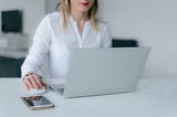 Woman siting in front of a laptop with her hand on the mouse.