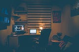 A dimly lit office space set up in a small room.