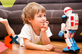 Image of a young boy lying on the floor, talking to his toy robot.