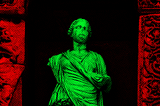 An ancient statue, with various features missing, such as the nose and the right arm.