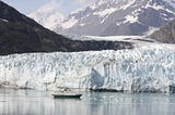A ship in front of glaciers and mountains in Glacier Bay, Alaska.
