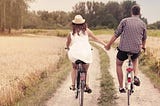 Two people riding bikes with holding their hands