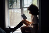 Woman reading a book in windowsill