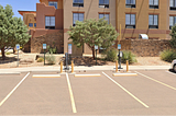 Image of the outside of the side of a hotel parking lot with two EVchargers