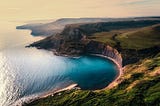 An aerial image of a green cliff overlooking the beautiful blue sea.