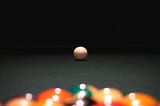 Colorful balls set up on a pool table; the white ball is prepared for the shot.