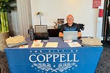 Luay Rahil sitting behind a table while hosting a job fair at the city of Coppell.