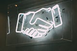 Neon light display creating the outline of a handshake