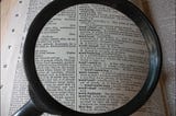 A magnifying glass focusing on a page in the dictionary