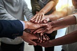 Group of people placing this hands in the centre, symbolizing unity/teamwork/agreement