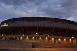 Arizona State Univerity arena at dusk with illuminating lights with a cloudy background