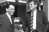 Black-and-white photograph of Frank Sinatra standing beside John F. Kennedy in Las Vegas during the 1960 presidential campaign, with both men smiling and dressed in formal attire.