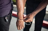 Closeup photo of hands being handcuffed by person behind