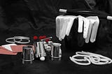 Color photo of the magician’s tools of the trade; top hat, white-tipped wand, white gloves, rings and playing cards.