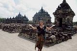 a woman (me) smiling and making the “I don’t know” gesture in front of a temple in Java, Indonesia