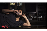 A rebellious young man is guzzling a daiquiri. He is lying on top of the bar and the words treat yourself apear next to him