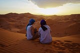 two people on a sand dune in the desert together. that could be you and me.