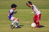 two six year olds play one on one soccer