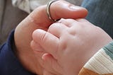Close-up photo of the author holding a baby’s hand