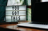 Sign saying “You got this” next to laptop