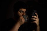 Holding phone while sipping tea, blacked out background