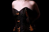 A photo of a white Irish woman wearing a brown textured corset looking away from the camera