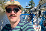 Author with partner in the background sailing boat away from harbor