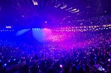 An arena full of people with blue and pink lighting mixed in halves