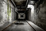 A long dark city alley underground, walls in decay on either side, a puddle in the foreground.