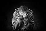 Black and white image of a person covering their face.