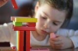 A little girl stacks toy blocks