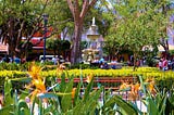 A bustling urban square in Antigua with fountains, flowers, and benches